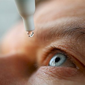 Close up of a man putting eye drops in eye